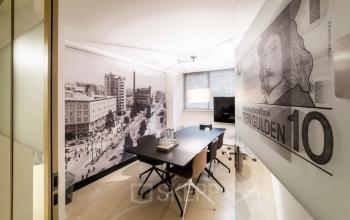 Modern office space rental at Coolsingel 104, Rotterdam Center, featuring a large table with chairs, black and white wall art, and a TV.