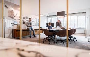 Modern workspace in the office at Coolsingel 104, Rotterdam Center, with three professionals collaborating at a desk surrounded by large windows, natural light, and stylish decor.
