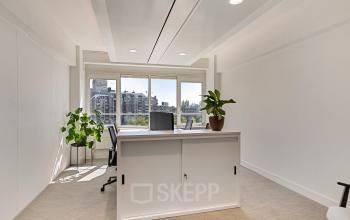 Bright furnished office space rental at Coolsingel 104, Rotterdam Center, with large windows, a few chairs, desks, and plants.