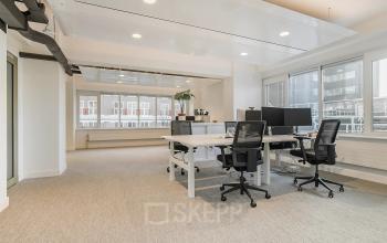 Bright and airy office space for rent at Coolsingel 104, Rotterdam Center, featuring modern furnishings and large windows providing ample natural light.