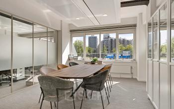 Modern conference room with large wooden table and chairs, offering a bright space for office space rental at Coolsingel 104, Rotterdam Center.