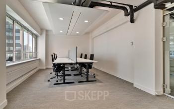 Bright office space at Coolsingel 104 in Rotterdam Center featuring rows of desks and chairs ideal for office space rental.