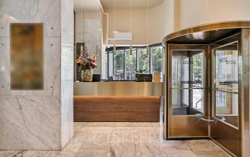 Reception area with marble flooring and a revolving door at the office to rent on Coolsingel 104, Rotterdam Center.