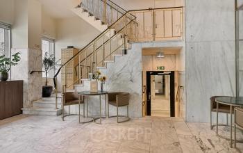 A stylish entryway with marble floors and walls at an office space available for rent on Coolsingel 104, Rotterdam Center.