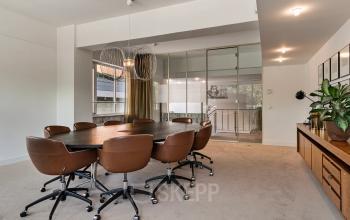 Spacious conference room at Coolsingel 104, Rotterdam Center, featuring a large oval table with comfortable chairs, ideal for office space rental.