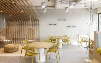 Bright modern office space at Westblaak 180 in Rotterdam Center with natural wood accents, circular tables, and stylish yellow chairs available for rent.