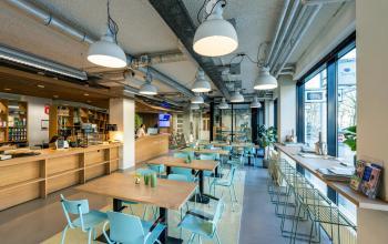 Bright office space with modern lighting, wooden accents, and pastel-colored seating at Westblaak 180, perfect for office space rental in Rotterdam Center.