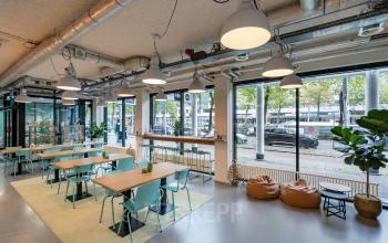 Interior workspace at Westblaak 180, Rotterdam Center with modern furnishings, large windows, and ample seating. Office space rental available.
