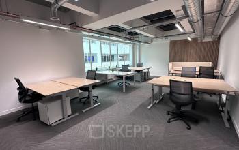 Spacious office to rent at Beursplein 37 in Rotterdam Center, featuring modern workstations, large windows, and industrial-style ceiling details.