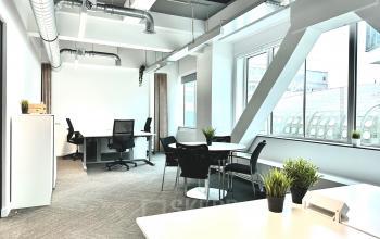 Modern furnished office space rental at Beursplein 37, Rotterdam Center, featuring large windows, multiple desks, and potted plants.