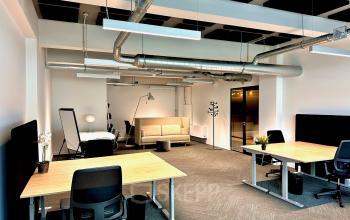 Modern office with multiple workstations, ergonomic chairs, wooden desks, and overhead lighting at Beursplein 37 in Rotterdam Center.