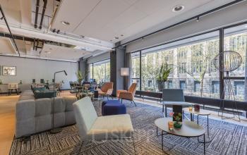 Modern furnished office space rental at Beursplein 37, Rotterdam Center, featuring stylish chairs, sofas, and large windows offering a view outside.