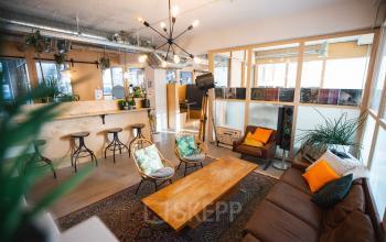 Bright and inviting lounge area with comfortable seating, wooden furniture, and a bar counter in the office space at Schiedamse Vest 154, Rotterdam Center.