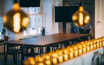 Modern office space rental at Schiedamse Vest 154 in Rotterdam Center with a large wooden table, black chairs, and decorative lighting.