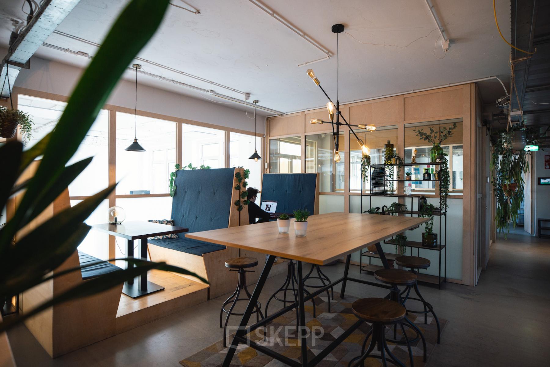 Modern furnished office space with a communal table, lounge seating, and natural lighting at Schiedamse Vest 154, Rotterdam Center. Ideal for office space rental.
