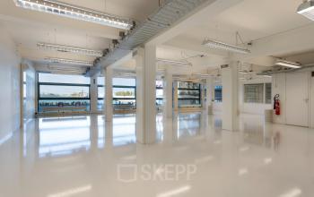 Interior view of a spacious, light-filled office at Lloydstraat 21 B, Rotterdam Delfshaven, available for office space rental. Large windows provide ample natural light.