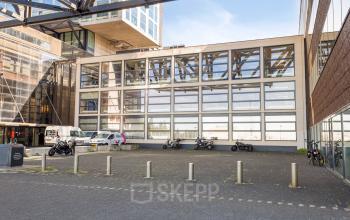 Exterior view of the office building at Lloydstraat 21 B, Rotterdam Delfshaven, featuring a modern facade and parking area. Ideal for office space rental opportunities.