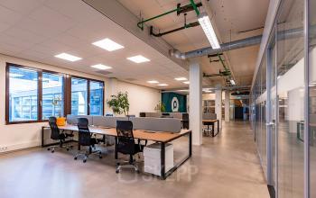 Modern office space for rent at Kratonkade 7 - 27 in Rotterdam Delfshaven, featuring furnished workspaces with large desks and natural light.