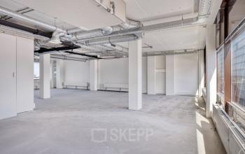 Unfurnished office space available for rent at Kratonkade 7 - 27 in Rotterdam Delfshaven, featuring large windows and industrial exposed ducts.