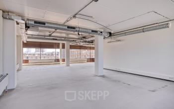 Spacious office to rent at Kratonkade 7 - 27 in Rotterdam Delfshaven, featuring an open floor plan with large windows.