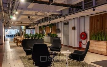 Furnished office space at Van Nelleweg 1, Rotterdam Delfshaven with seating arrangement, greenery and tables, ideal for office space rental.