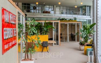 Bright office space for rent at Van Nelleweg 1, Rotterdam Delfshaven, featuring modern furnishings, plants, and ample natural light.