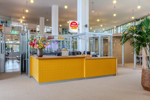 Spacious and bright office to rent at Van Nelleweg 1, Rotterdam Delfshaven, featuring a welcoming yellow-tiled reception area with glass partitions and decorative plants.