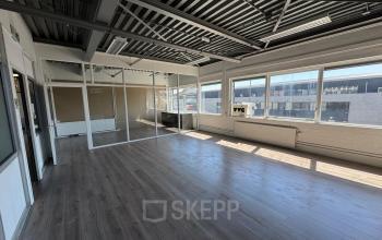 Spacious and sunlit office space with large windows, available for rental in Rotterdam Delfshaven at Van Helmontstraat. The area features natural light and potential for flexible workspace configurations.