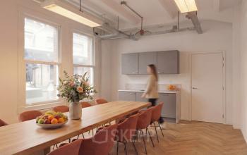 Bright office space at Lloydstraat 5 in Rotterdam Delfshaven featuring a long table, chairs, and a kitchenette.