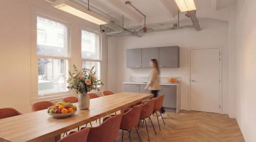 Bright office space at Lloydstraat 5 in Rotterdam Delfshaven featuring a long table, chairs, and a kitchenette.