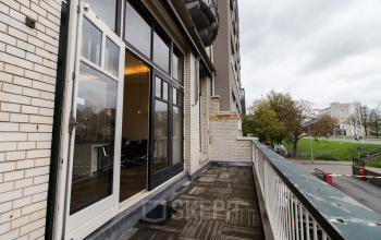 Balcony view of Haringvliet 76, Rotterdam, showcasing exterior features suitable for office space rental. Includes large windows and a view of nearby greenery.