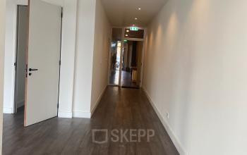 Interior hallway at Haringvliet 76, Rotterdam, showcasing sleek wooden floors and white walls, ideal for navigating to various office spaces.