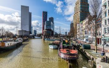 Scenic view of Rotterdam Haringvliet area featuring boats on the water and a backdrop of modern office buildings, suitable for those seeking office space rental opportunities.