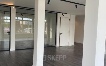 A modern interior space at Haringvliet 76, Rotterdam featuring sleek wooden flooring, large glass partitions, and a minimalist design, suitable for office space rental.