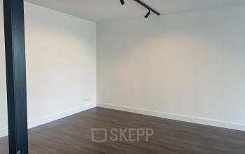 Minimalist interior space at Haringvliet 76, Rotterdam, suitable for office space rental, featuring sleek wooden flooring and modern track lighting, ideal for customizing into a productive work environment.