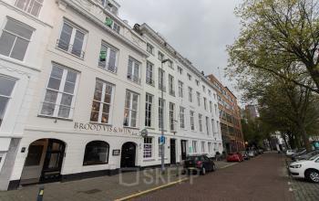 Street view of Haringvliet 92, Rotterdam, showing a white, multi-story office building with an elegant facade, ideal for office space rental.