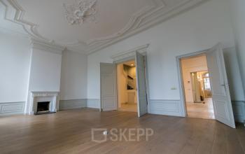 Spacious interior room at Haringvliet 92, Rotterdam, featuring intricate ceiling moldings, wooden flooring, and fireplace, ideal for office space rental.