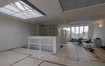 Office space at Haringvliet 92 in Rotterdam with large windows, high ceilings, and an open layout for workspace rental. Minimalistic design with potential for customization.