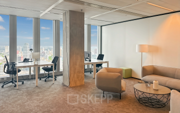 Bright office space at Wilhelminakade 173 in Rotterdam Kop van Zuid, featuring desks, chairs, and a comfortable seating area with a view of the city skyline.