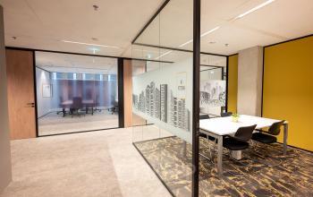 Interior view of a modern office space with glass partitions, a small meeting room with a table and chairs at Wilhelminakade 173, in Rotterdam Kop van Zuid.