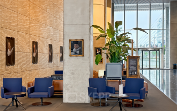 Modern office space at Wilhelminakade 173, Rotterdam Kop van Zuid, featuring stylish seating and decor for rent. Large plant adds a fresh touch to the open lobby area.