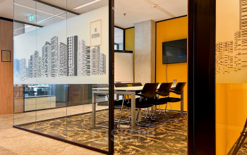 Modern furnished office space for rent at Wilhelminakade 173, Rotterdam Kop van Zuid, featuring a glass-enclosed conference room with a city skyline design and a large table with chairs.