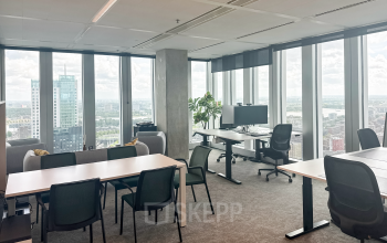 Modern office space at Wilhelminakade 173, Rotterdam Kop van Zuid, featuring large windows and multiple desks, ideal for workspaces. A perfect spot for office space rental with a panoramic city view.