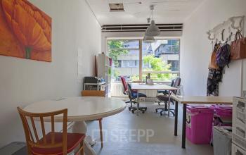 Interior office space rental at Zomerhofstraat 71, Rotterdam North, featuring desks, chairs, and decorative items in a bright room with large window.