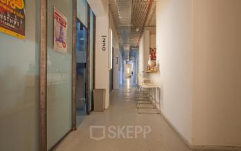 Interior hallway of office space rental at Zomerhofstraat 71, Rotterdam North, Rotterdam with industrial design, high ceilings and a modern ambiance featuring bar stools along the wall.