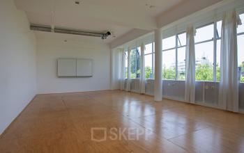 Spacious unfurnished office space with large windows and light wooden flooring located at Vijverhofstraat 47, Rotterdam North. Ideal for office space rental.
