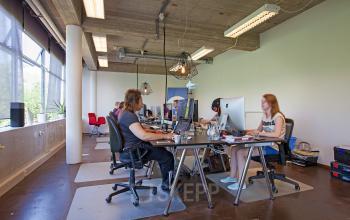 Modern office space at Vijverhofstraat 47, Rotterdam North, featuring large windows, several workstations, and professionals engaged in business activities.