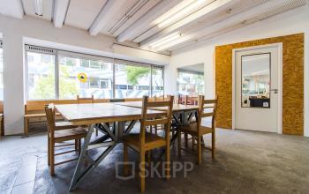 Spacious office to rent at Zomerhofstraat 84, Rotterdam North, featuring a large table with wooden chairs and ample natural light.