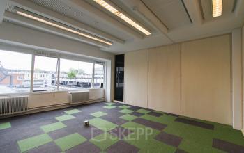 Bright and spacious office space with large windows, green and brown checkered carpet, located at Zomerhofstraat 84, Rotterdam North.