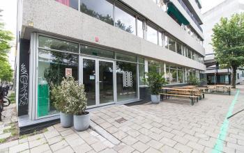 Exterior of office located at Zomerhofstraat 84, Rotterdam North, Rotterdam, featuring large glass windows, entrance, and outdoor seating area.